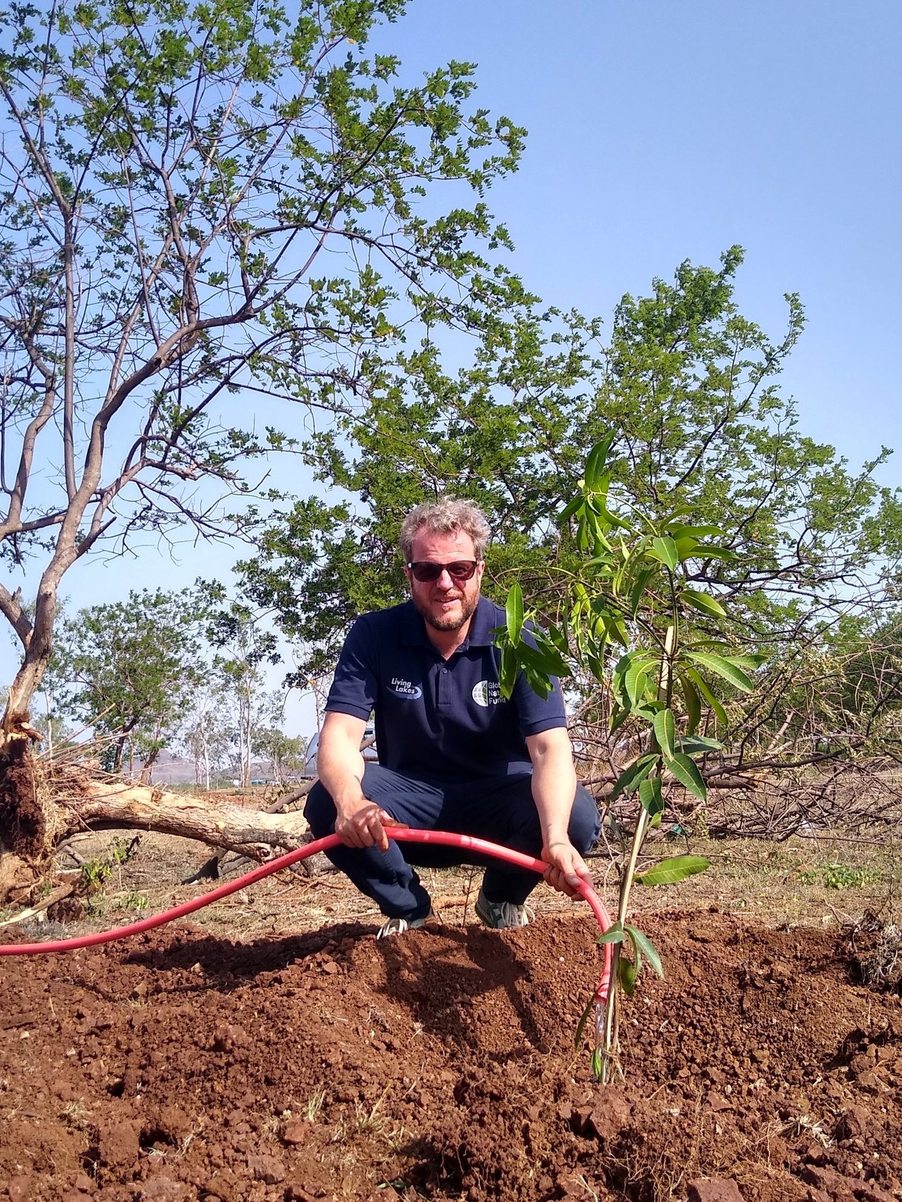 Ein Mitarbeiter des Global Nature Fund wässert einen jungen Baum