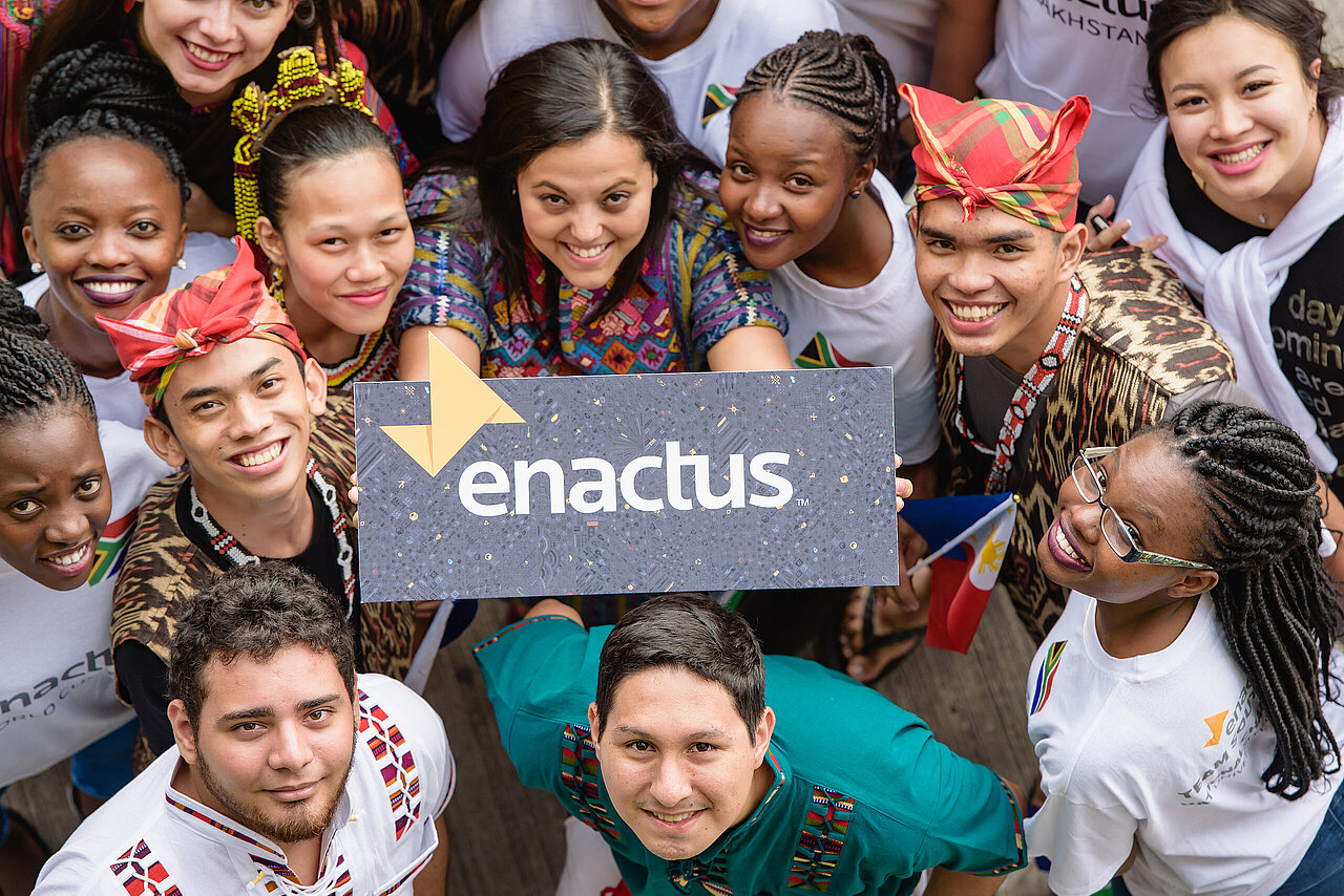 Enactus Studierende halten das Logo "enactus" nach oben
