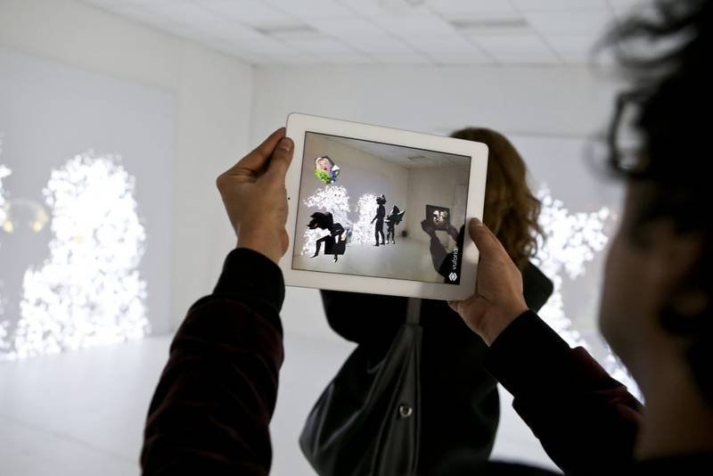 Eine Person hält ein Tablet, das virtuelle Personen darstellt