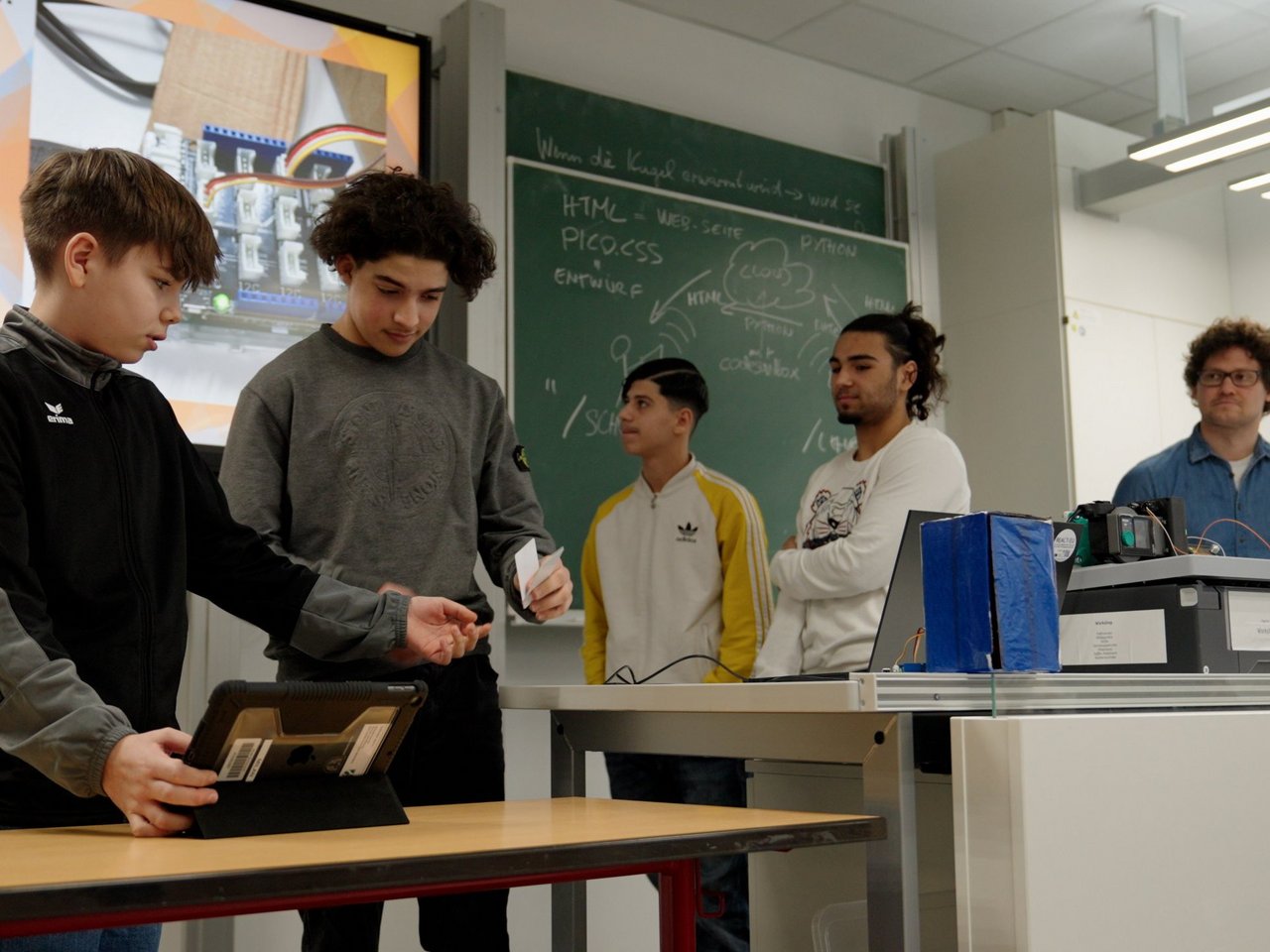 Eine Gruppe Schüler stellt ihr Projekt im Klassenraum mit einer Präsentation vor 