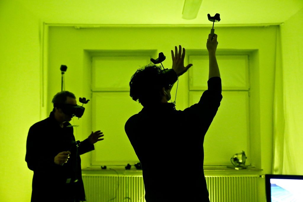 Zwei Menschen mit VR-Brillen in einem neongrün belichteten Raum
