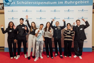 Schülerstipendiaten der RuhrTalente auf einem roten Teppich vor einem Banner mit dem Logo der RuhrTalente
