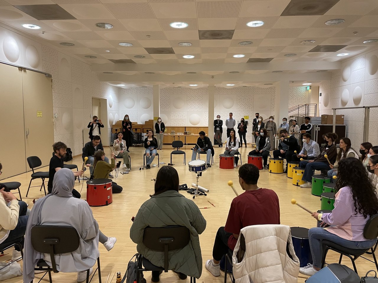 Die Schülerstipendiaten sitzen im Halbkreis vor Trommeln bei einem Musik-Workshop im Orchesterprobenraum des Konzerthaus Dortmund