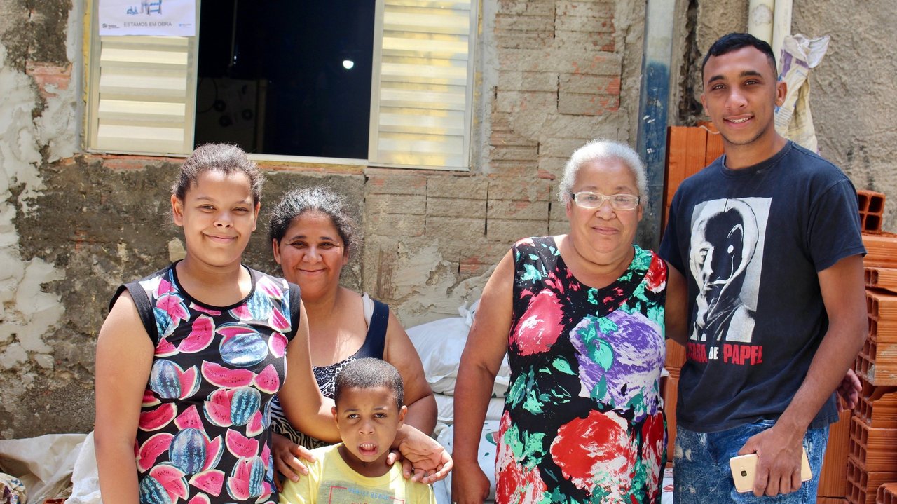 Eine Familie einer Favela in Brasilien steht vor einem Haus, das bald renoviert wird