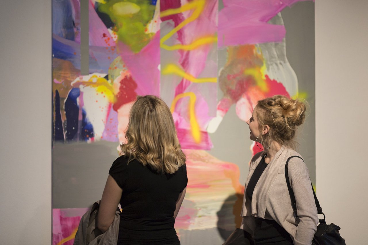 Zwei Frauen stehen vor einem großflächigen abstrakten Kunstwerk