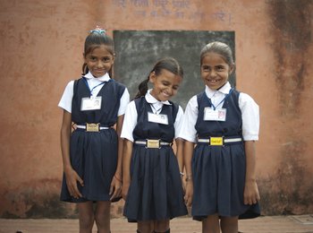 Drei Grundschulkinder in Schuluniform lachen