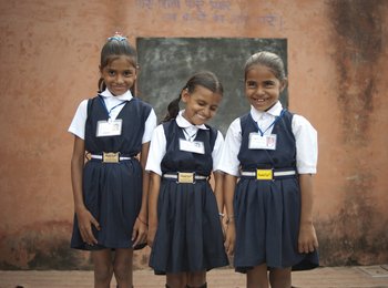 Drei Grundschulkinder in Schuluniform lachen
