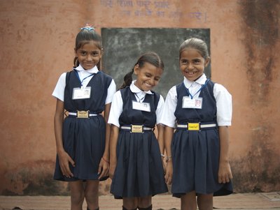 Drei Grundschulkinder in Schuluniform lachen