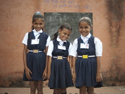 Drei Grundschulkinder in Schuluniform lachen