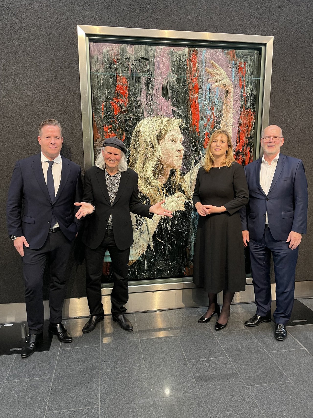 Oliver Hermes, Oliver Jordan, Evi Hoch und Wolfgang Mertineit stehen vor einem Gemälde des Hausmalers des Konzerthaus Dortmund, Oliver Jordan, das die Dirigentin Mirga Gražynitė-Tyla porträtiert